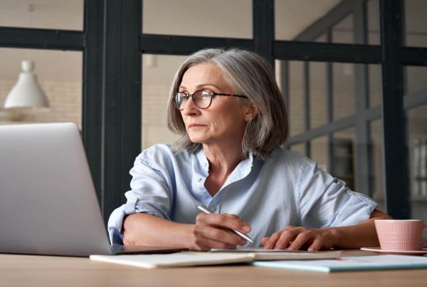 Business woman taking notes while watching laptop sitting at table